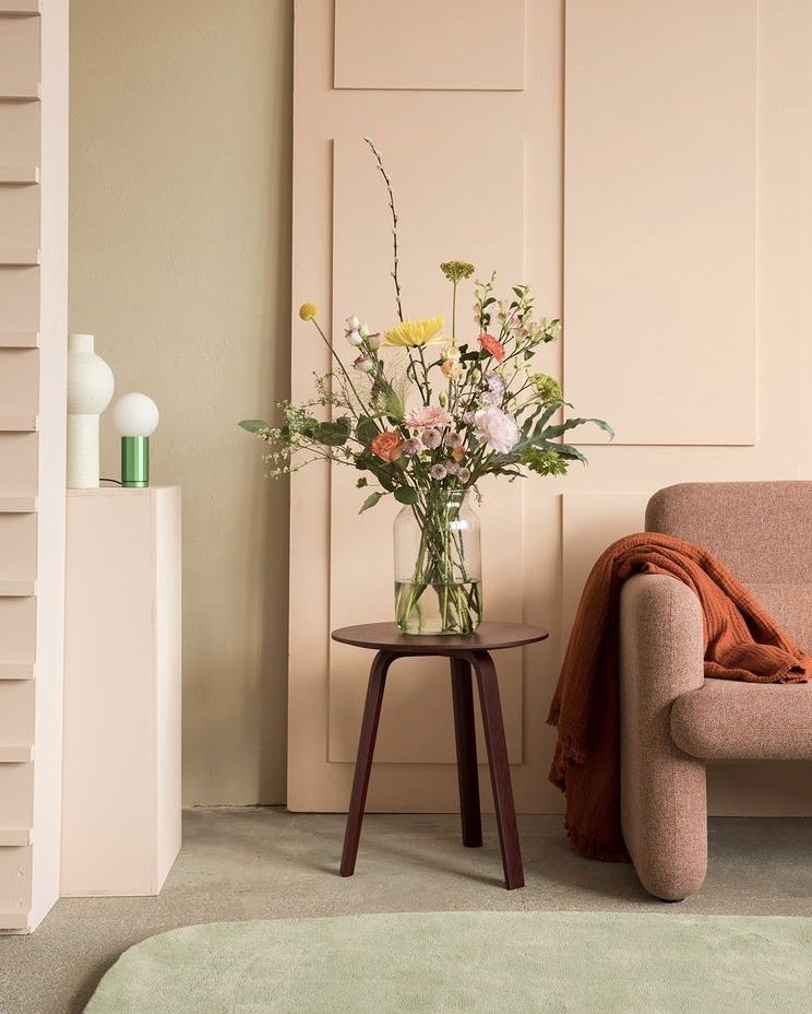 image montrant un canapé rose et des murs vert sauge et rose poudré avec un bouquet posé sur une console